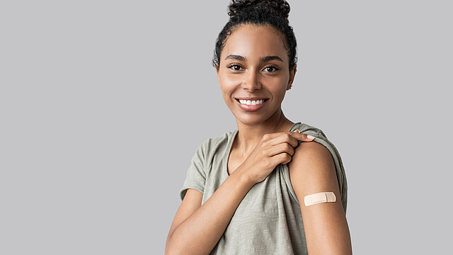 Portrait of a young woman with plaster on her arm after getting a vaccine.